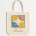 Hero shot of a cotton canvas tote bag printed with a sun-washed ochre and azure terrazzo pattern on a plain background