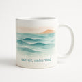 Sea-glass green ceramic mug with subtle tonal coastal slow down motif on a pale table