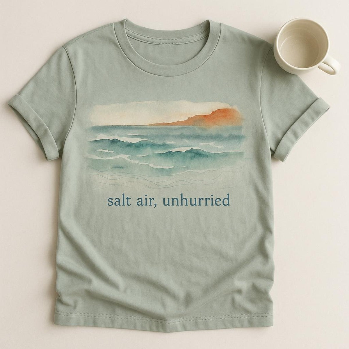 Folded t-shirt beside a shell and linen towel showing scale and colour