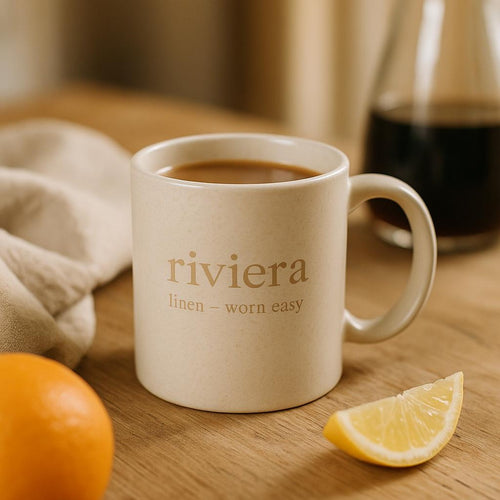 Riviera linen mug styled on a sunlit kitchen counter beside folded linen napkins