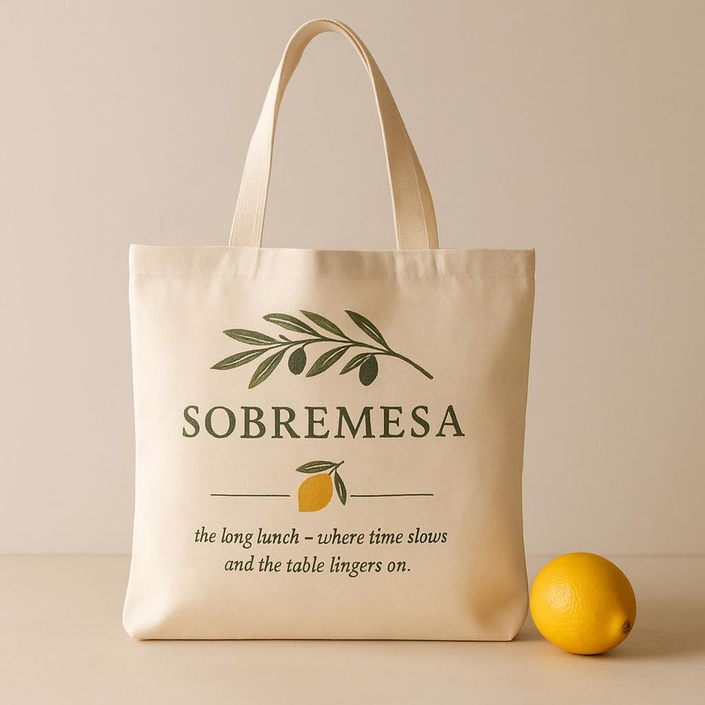 Tote bag held open to reveal a bottle of wine, bread and wildflowers inside