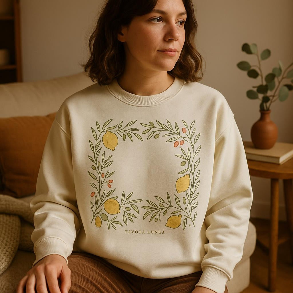 Person wearing the Mediterranean lemon and olive sweatshirt at a sunlit outdoor lunch table