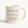 Sea blue ceramic mug with Cove-to-Cove coastal escape artwork on a white background