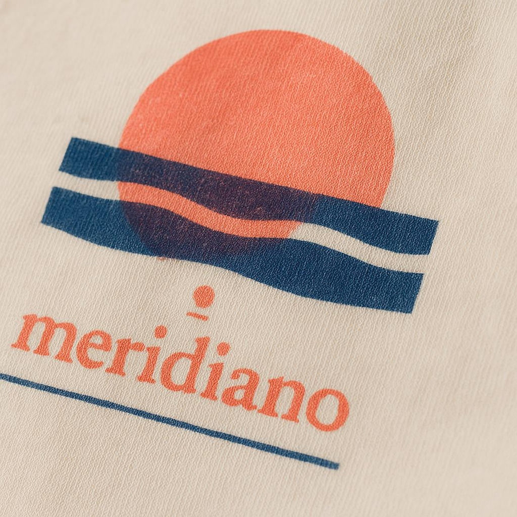Close-up of the tiny tonal embroidered coastal marker stitched discreetly at the hem of the tee