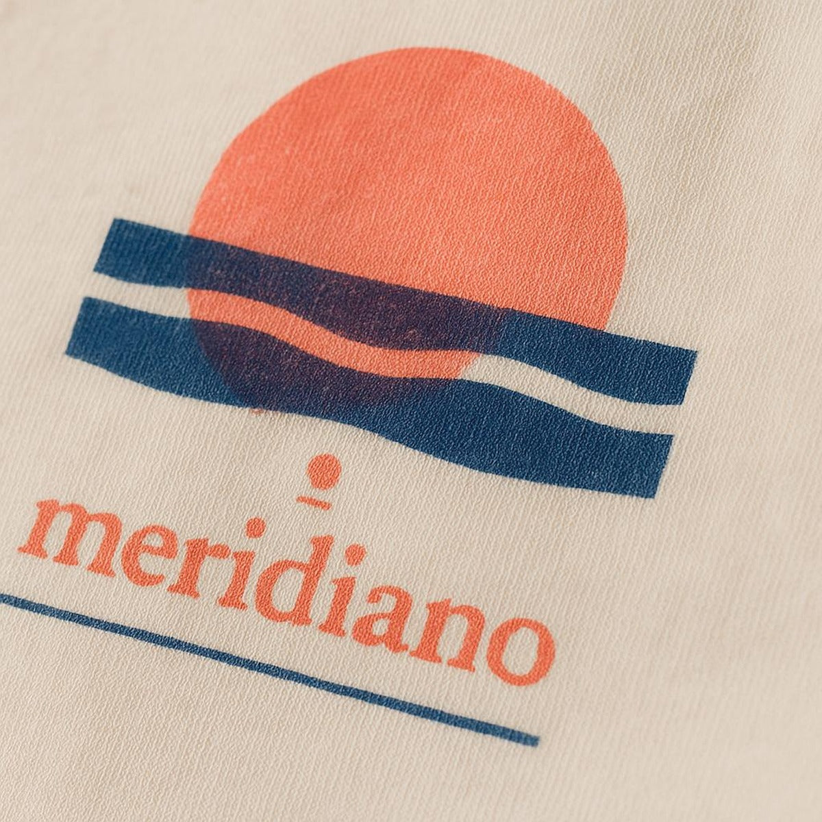 Close-up of the tiny tonal embroidered coastal marker stitched discreetly at the hem of the tee