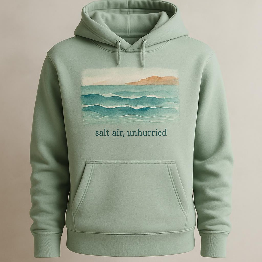Folded hoodie next to a linen towel and seashells to show scale and texture