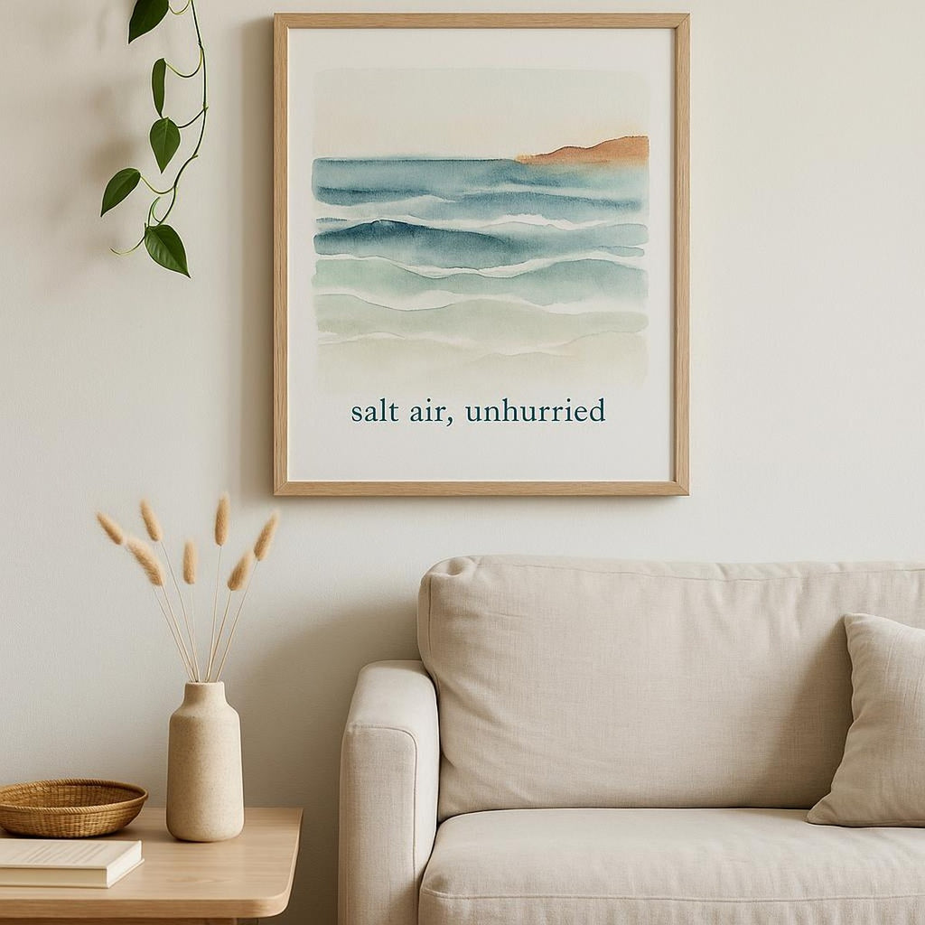 Lifestyle scene showing the coastal poster framed above a linen bed in a calm, sunlit room